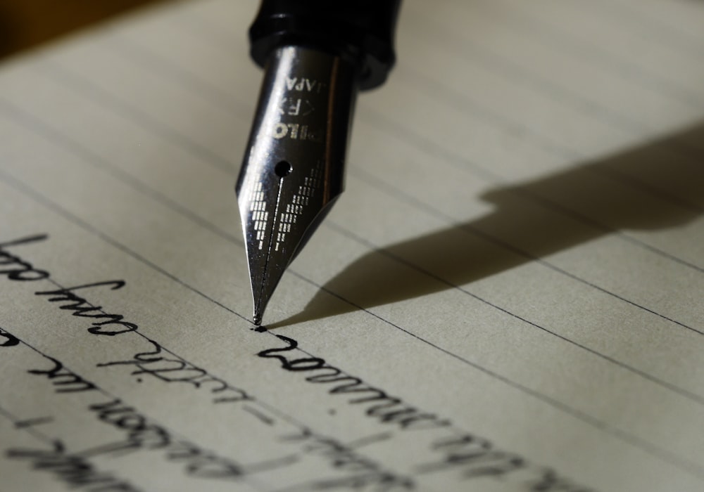 A woman writing thoughtfully at a desk in warm natural light